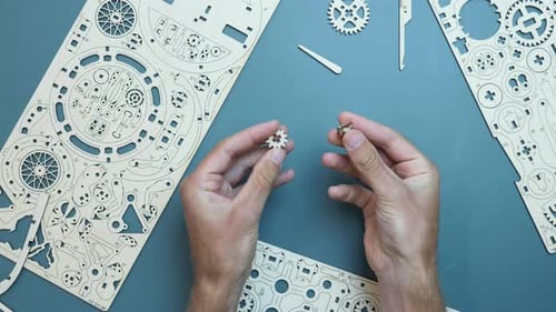 Mains assemblant de petits détails d'un jouet mécanique en bois