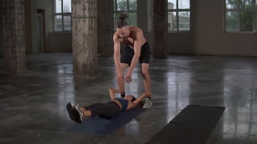 Woman Doing Leg Raises with Trainer Supervising