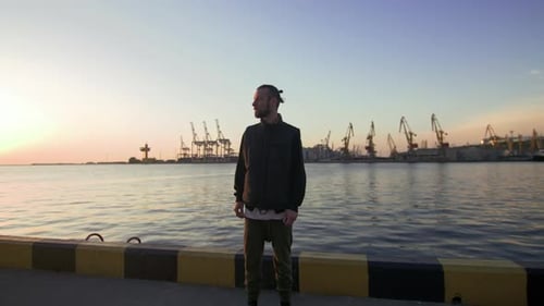 Homme Hipster élégant sur fond de port maritime pendant le coucher du soleil regardant de côté