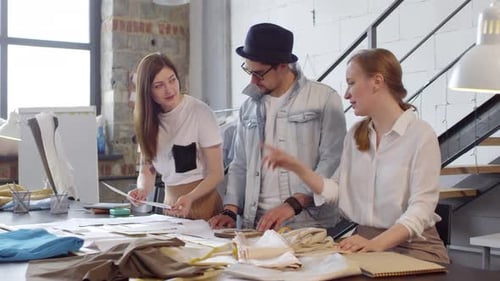 Team of Designers Discussing Fashion Sketches in Sewing Workshop