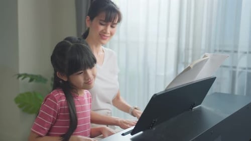 Child Plays Piano with Gentle Adult Guidance