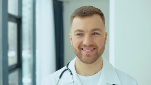 Successful Physician in White Lab Coat Looks at the Camera and Smiles in Hospital Office