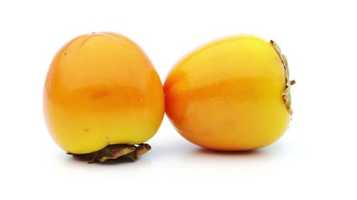 Rotating Persimmon Fruit against a White Background