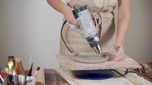 Woman Making a Ceramic Plate with Heat Gun