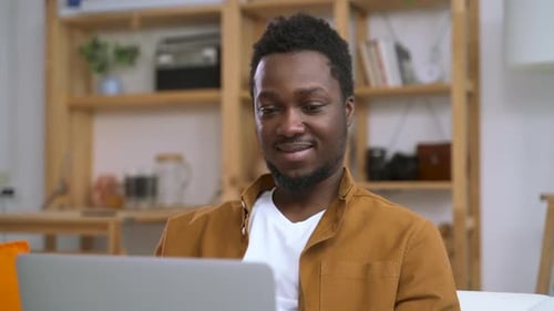 African American Man Typing on Laptop and Check Information on Screen in Living Room Spbas