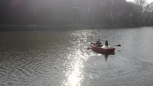 Aerial Shot of Brides Swim in a Red Boat. The Bright Sun Is Reflected in the Lake Creating