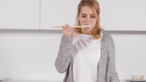 Woman Tastes Food in a Modern Kitchen