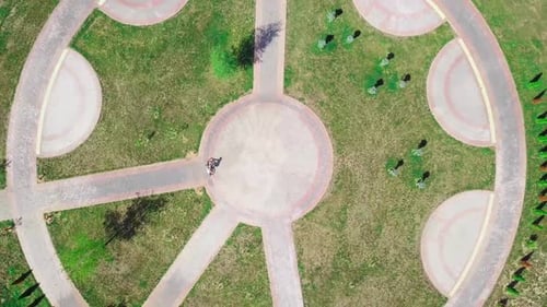 Vue de dessus d'une femme à vélo faisant du vélo sur une route circulaire dans un parc de la ville.