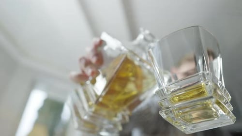 Tournage sous la table vitrée d'un homme flou versant du whisky d'une carafe dans un verre et prenant un verre