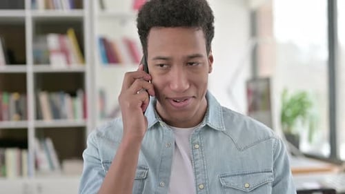 Young Adult Talking on Mobile Phone Indoors