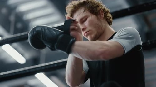 Serious Fighter Waiting for Fight at Gym. Kickboxer Wearing Boxing Gloves