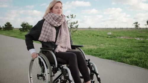 Young Disabled Woman Is Riding on Wheelchair in Park Area in Spring Time