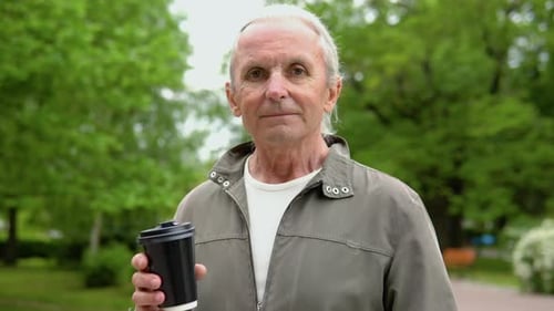 An Elderly Man Drinks Coffee in the Park