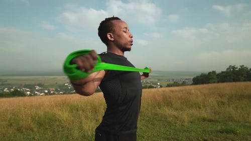 Side View of African Man Working Out with Rubber Expander