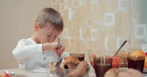 Young Child Eating at a Table Full of Food