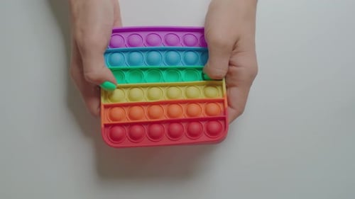 Top View of Female Hands Playing with Popular Silicone Antistress Toy Pop It