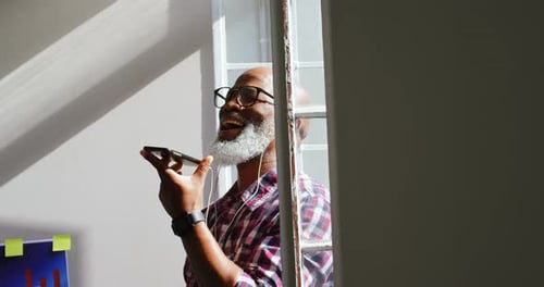 Man Talks on Phone with Headphones in Bright Office