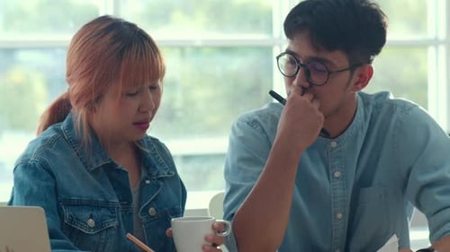 Young Asian creative team meeting working on laptop at office.