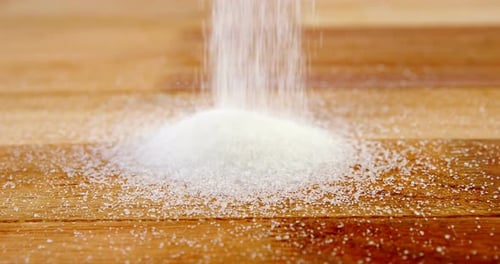 Sugar pouring on a wooden table