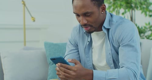 Young Adult Relaxing at Home Using Mobile Phone