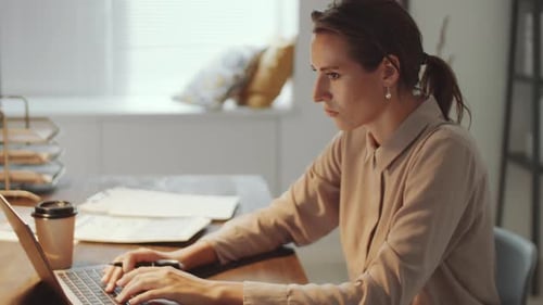 Focused Woman Working at Desk with Laptop