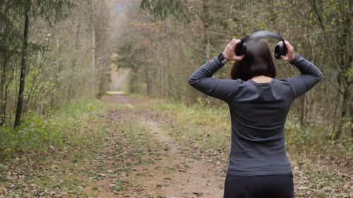 Woman puts on her headphones, activates her fitness app on the smartwatch and starts her run through