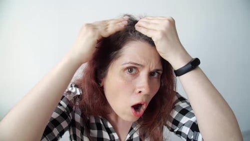 Shocked Woman Looks at Her Gray Hair Roots