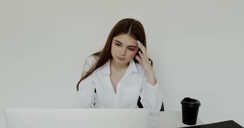 Young Girl Works with Laptop Near Cup of Coffee on Background in Office