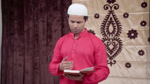 Man in Red Robe Reading Religious Book