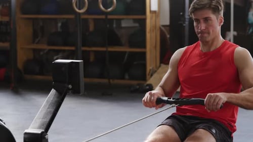 Front view athletic Caucasian man exercising on a rowing machine