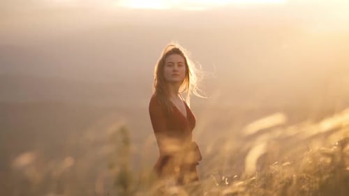 Young Romantic Woman in a Red Dress Walks Across the Field at Sunset