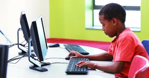 Young Child Typing on Computer in School Lab