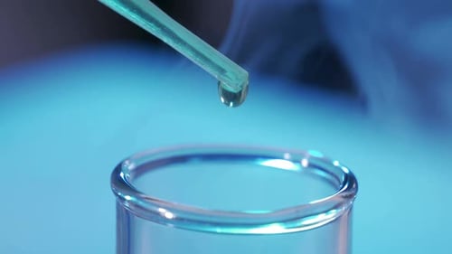 In a Laboratory a Scientist with a Pipette Analyzes a Colored Liquid