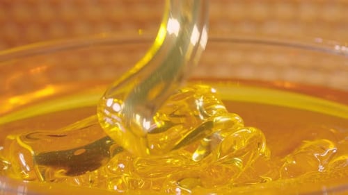 Thick Golden Honey Flowing Into a Glass