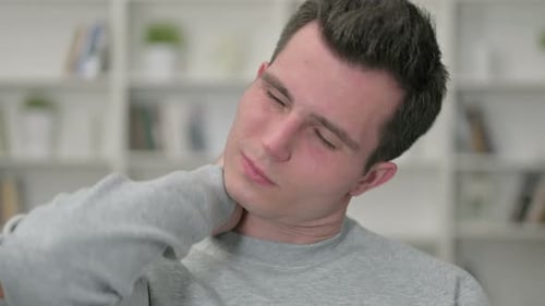 Young Man Massaging Sore Neck Muscles Close Up