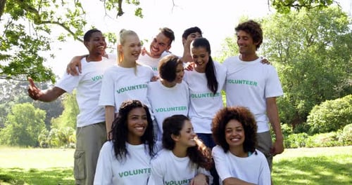 Diverse Volunteers Smiling and Waving Outdoors in Park