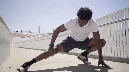 Concentrated African American Man Stretching Legs on Bridge