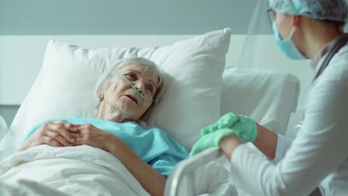 Senior Woman Lying on Hospital Bed and Talking with Nurse