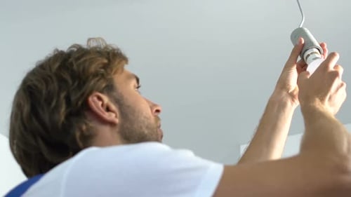 Man Changes Light Bulb in Apartment