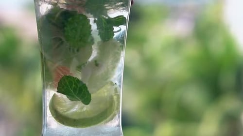 Une paille orange en plastique mélange lentement un cocktail de mojito congelé