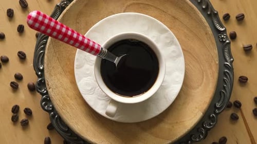 Top View of Coffee with Spoon on Decorative Plate on Wooden Table