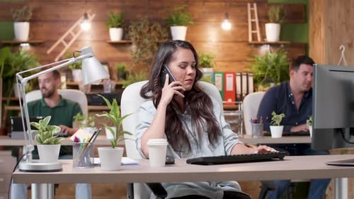 Woman Talks on the Phone in a Busy Cozy Office