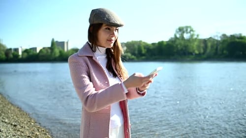 Young Woman Uses Phone by Scenic Riverside