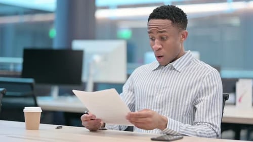 Young Adult Reading Bad News on Documents at Work