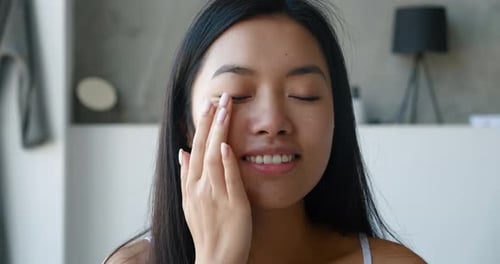 Woman Applies Cream to Her Face in Home
