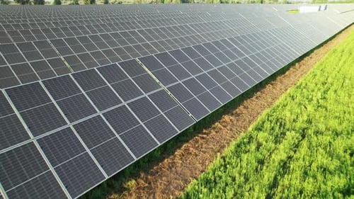 Luftbild Solarkraftwerk auf der grünen Wiese bei Sonnenuntergang Sonnenkollektoren in Reihe