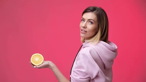 Woman Holds an Orange Half in Studio