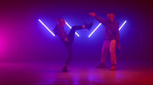 Dynamic Duo Dancing with Neon Lights in Studio
