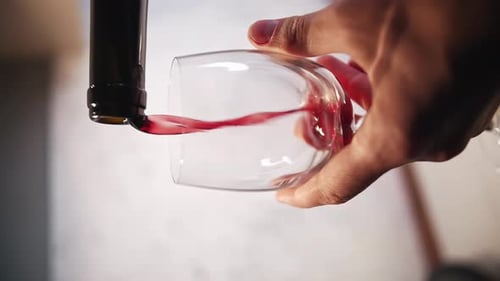 Gros plan du versement de vin rouge d'une bouteille dans un verre