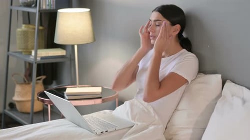 Woman Working on Laptop in Bed Has Headache